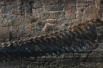 Old and rusty chain hanging at the side of the dock