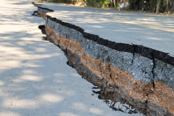 Asphalt road collapsed with cracks and hole in sunny day. 