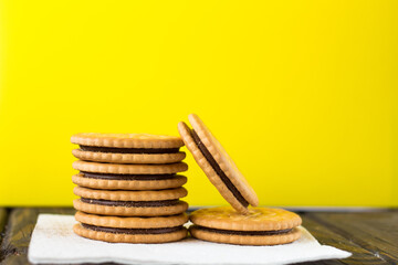 Sandwich biscuits with a chocolate filling on a yellow background.