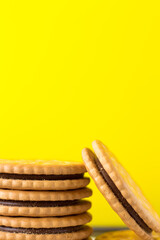 Sandwich biscuits with a chocolate filling on a yellow background.