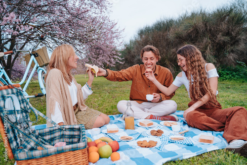 Family picnic celebrating Mother's Day with their son and daughter, while they enjoy a sunny day eating healthy food next to an almond tree.