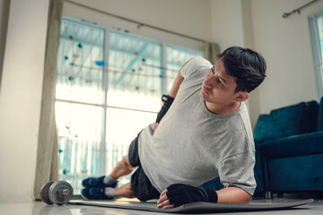 Young man making abdominal exercises on yoga mat in living room at home. Fitness, workout and traning at home concept.