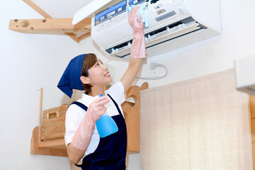 エアコンを掃除するハウスキーパー（家政婦）の女性
