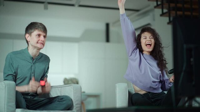 happy couple playing video game with controller on play station at home