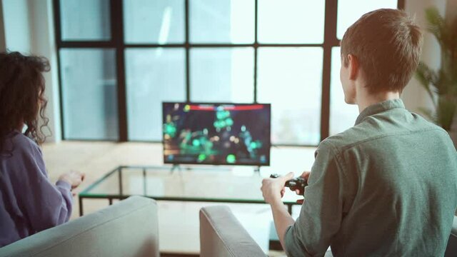 happy couple playing video game with controller on play station at home