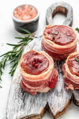 Fresh pieces pork ready to cook. Sirloin medallions steaks wrapped in bacon on woden board on a light background, filet Mignon. top view