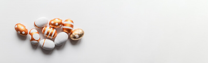 Pile of different drawing golden eggs on a white table. Happy Easter greeting card or poster