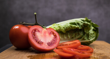 Tomatoes in slices and lettuce on a wooden board - studio photography
