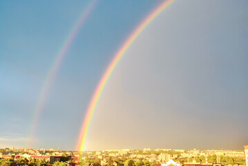 Double rainbow on dark blue stormy sky over Rivne town in Ukraine