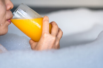 Action of woman is drinking orange juice during taking spa in jacuzzi bathtub, healthy liftstyle...