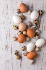 Easter picture with quail and chicken eggs on a light wooden background. The minimal concept of Easter. An Easter card with a place for the text.