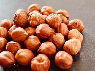 Heap of peeled hazelnuts on black background. Place for text