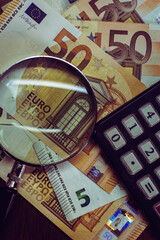 Euro bills seen through a magnifying glass and a calculator