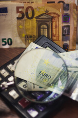 Euro bills seen through a magnifying glass and a calculator