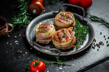 Medallions steaks from the beef tenderloin covered bacon on metal tray on Dark background. Top view