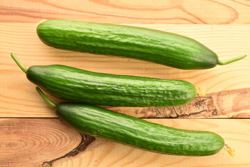 Three green cucumbers, close-up, on a wooden table, top view.