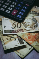 Bill of 50 Brazilian Real with a calculator and other bills under them