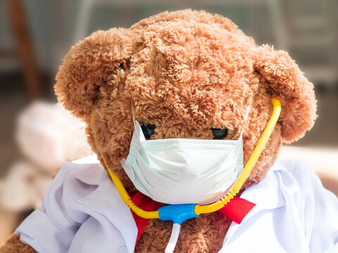 Close up big teddy bear wearing doctor gawn with face mask and stethoscope