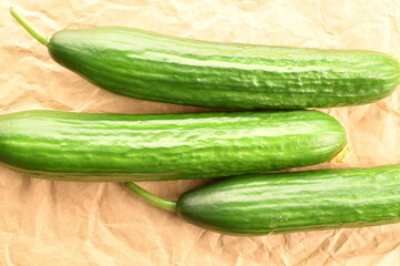 Three green cucumbers, close-up, on craft paper, top view.