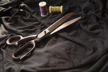Sewing vintage scissor, thread roll lines on black textile background - sewing equipment with space to text - sustainable method