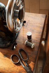 Sewing machine, wood table, scissor, thimble, thread roll and swing machine, accessories, on a sunny day, sustainable slow fashion equipment