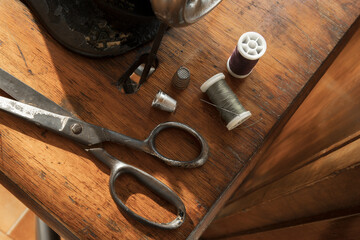 Sewing table, scissor, thimble, thread roll and swing machine, accessories, on a sunny day, sustainable slow fashion equipment