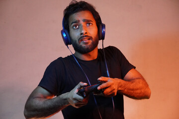 young man exited playing game at home with Joystick and wearing headphone