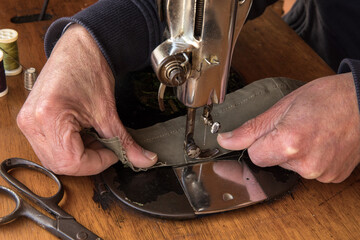 Man's hands behind sewing machine. Sew workshop. textile vintage sewing at home on wood table, sustainable sewing
