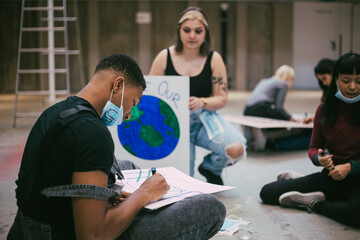 Male and female activist preparing poster during COVID-19
