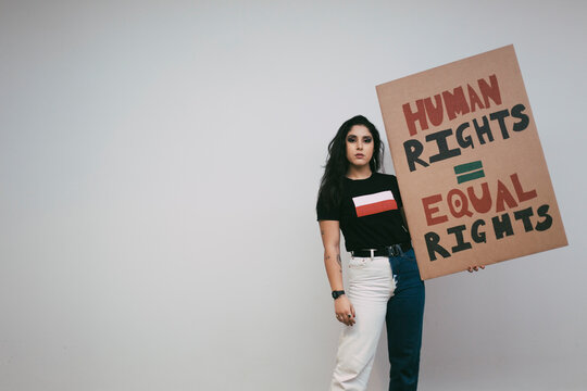 Portrait of female activist with human rights signboard against white wall