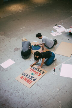 High angle view of female and male protestors making posters for equal rights and environmental issues