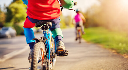 Fototapeta na wymiar Cute children riding on bicycles on asphalt road in summer.