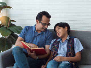 Indian dad reading to attractive son. Dad or teacher trying teaching to tired son or student.