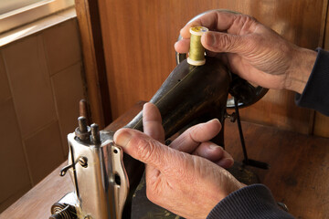 Finger holding sewing lines. Old man's hands behind sewing. Sew workshop. Textile vintage sewing industrial on wood table