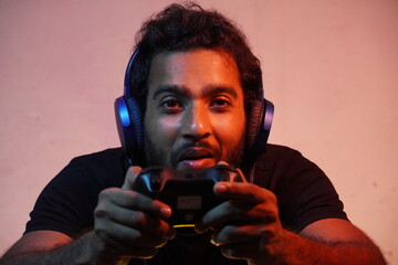 young man playing video game at home with Joystick and wearing headphone