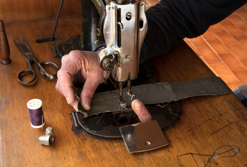 Old man's hands behind sewing. Finger on needle. Sew workshop. textile vintage sewing industrial on wood table