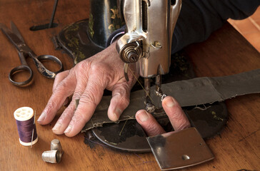 Old man's hands behind sewing. Fingers on needle. Sew workshop. textile vintage home sewing on wood table