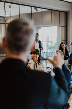 Cheerful male and female toasting wineglasses in party at office