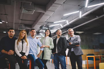 Obraz premium Happy male and female colleagues dressed in smart casual and formal clothes smiling at camera during team building brainstorming in office interior, successful business partners posing togetherness