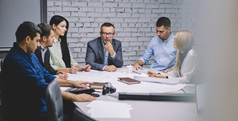 Male and female architects checking sketch working in team for planning, successful colleagues analyzing blueprint while cooperating on startup business project have productive brainstorming