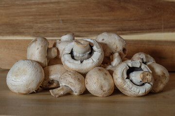 Pilze: Weiße Champignons (Zuchtchampignon - Lat.: Agaricus bisporus) auf Holz / hölzernen Hintergrund