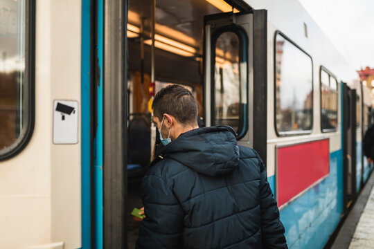 Mid adult man boarding tram during pandemic