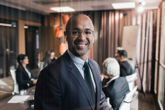 Portrait of smiling bald businessman against colleagues in board room