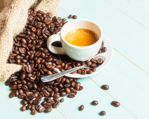 White cup of coffee,teaspoon and coffee bean on green background. Copy space.