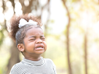 Close up, mix race African girl crying  with copy space as blurry background of the park. Lost or throwing tantrum to mom or dad.