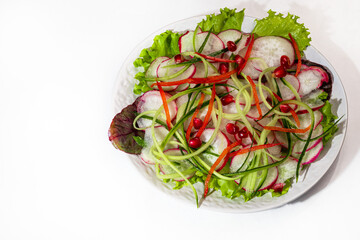 Vegetarian salad of radish, spinach, red onion and bell pepper and cucumber. On a light background.