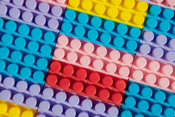 children's play background: the plane of plastic multi-colored bricks, blur, selective focus