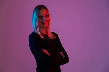 young blonde woman illuminated by neon lights looks at the camera