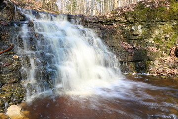 Spring, a waterfall in the forest, stones, moss. Long exposure