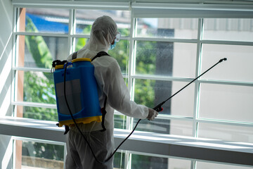 Asian healthcare medical workers wearing PPE protective suit disinfecting to building in new normal 